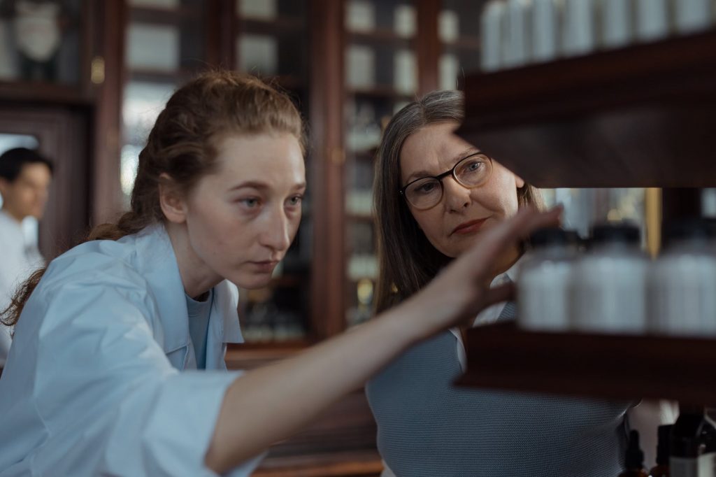 Women Looking at the Medicine Bottles at the Shelves
